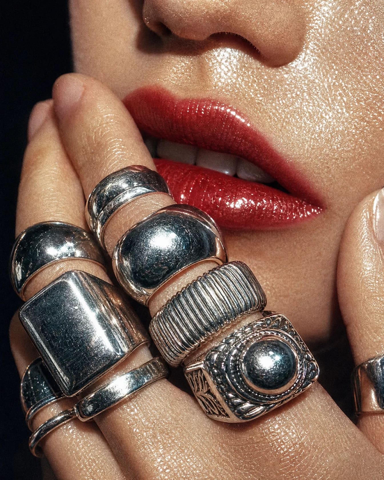 Close-up of chunky silver rings against glossy red lips