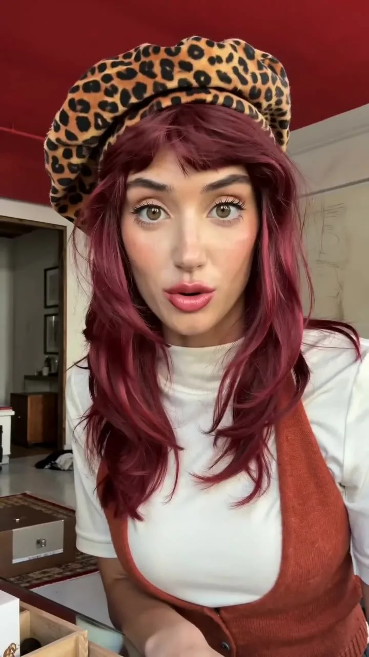 Creator with red hair and a leopard beret talking to camera